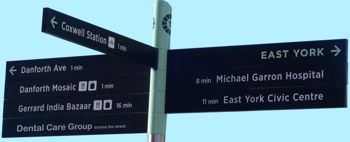 Direction street sign pointing to Danforth, East York, Coxwell Subway Station and Dental Care Group